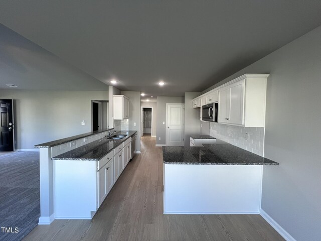194 Lotus Ave, Smithfield, NC 27577 - kitchen featuring stainless steel microwave, dark stone countertops, a sink, white cabinets, and a peninsula