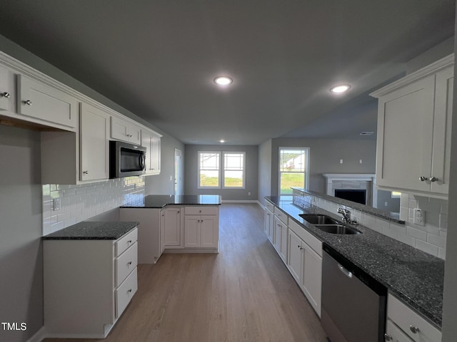 194 Lotus Ave, Smithfield, NC 27577 - kitchen with a peninsula, appliances with stainless steel finishes, dark stone countertops, a sink, and light wood-type flooring