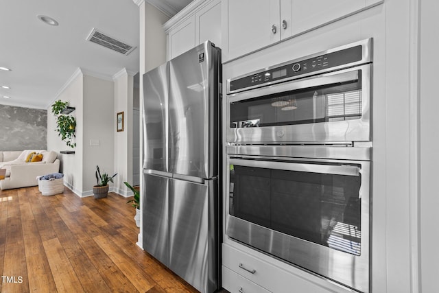 kitchen featuring stainless steel appliances, white cabinets, dark wood-type flooring, and crown molding