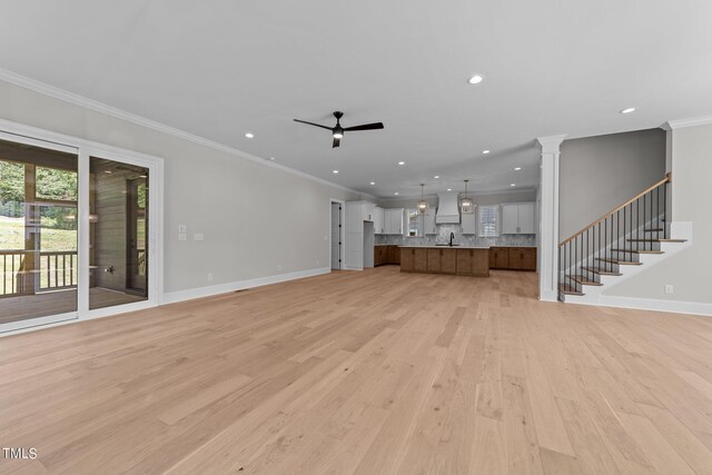 unfurnished living room with ceiling fan, light hardwood / wood-style flooring, crown molding, and decorative columns