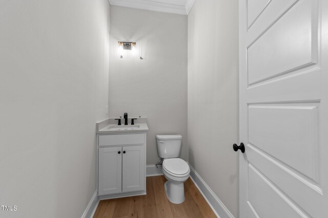 bathroom with vanity, hardwood / wood-style flooring, crown molding, and toilet