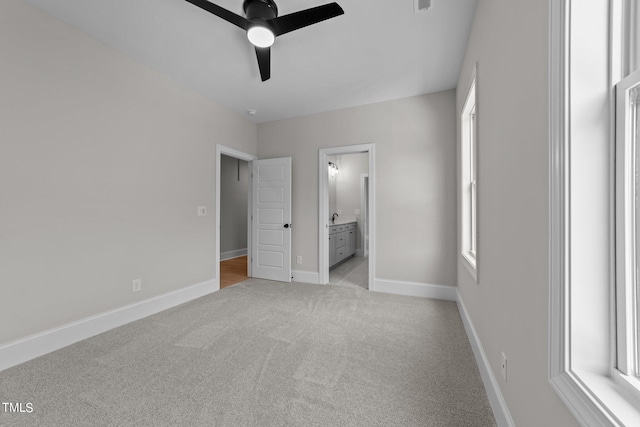 unfurnished bedroom with ensuite bath, ceiling fan, and light colored carpet