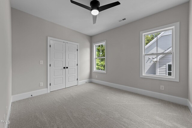 interior space with ceiling fan, carpet flooring, and multiple windows