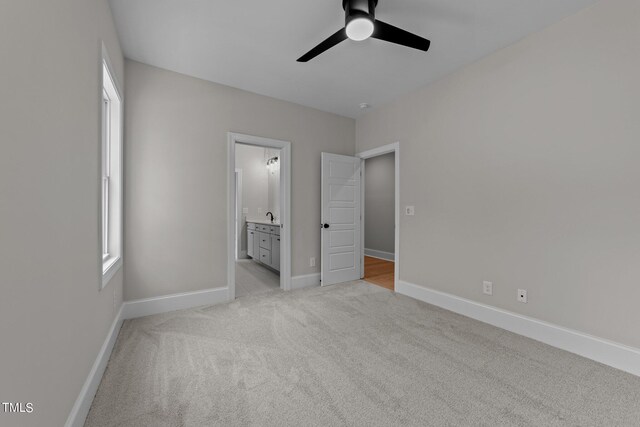 unfurnished bedroom with connected bathroom, ceiling fan, and light colored carpet