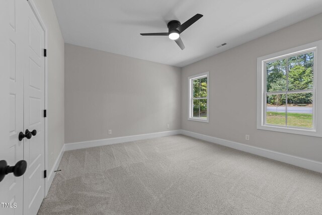 unfurnished room with ceiling fan, light colored carpet, and plenty of natural light