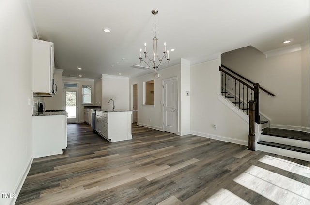 kitchen with sink, white cabinetry, a kitchen island with sink, and hanging light fixtures