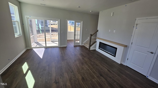 unfurnished living room with dark wood-style floors, a fireplace, stairs, and baseboards