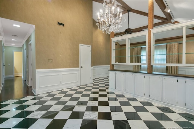 interior space featuring white cabinets, an inviting chandelier, a towering ceiling, and rail lighting