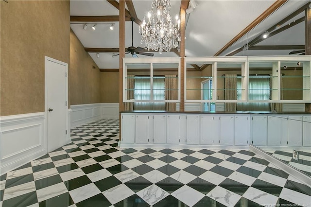 interior space featuring an inviting chandelier, white cabinets, lofted ceiling, and track lighting