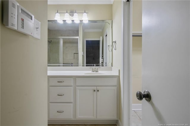 bathroom with vanity, a shower with shower door, ornamental molding, and tile patterned floors