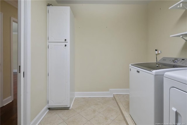 clothes washing area featuring separate washer and dryer, cabinets, and light tile patterned flooring