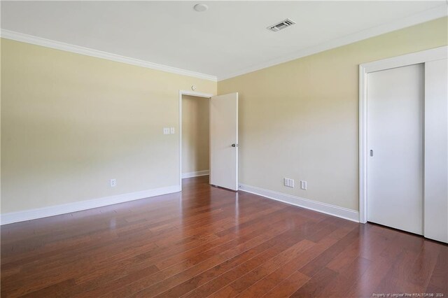 interior space featuring a closet, crown molding, and dark wood-type flooring