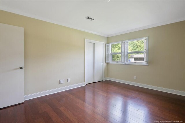 unfurnished bedroom featuring ornamental molding, dark hardwood / wood-style floors, and a closet