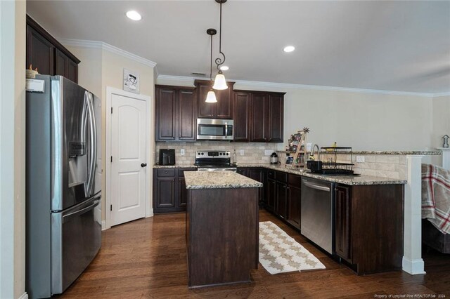 kitchen featuring dark wood-type flooring, stainless steel appliances, decorative light fixtures, and a center island