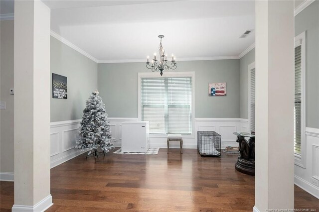 dining room featuring dark wood-type flooring, an inviting chandelier, and crown molding