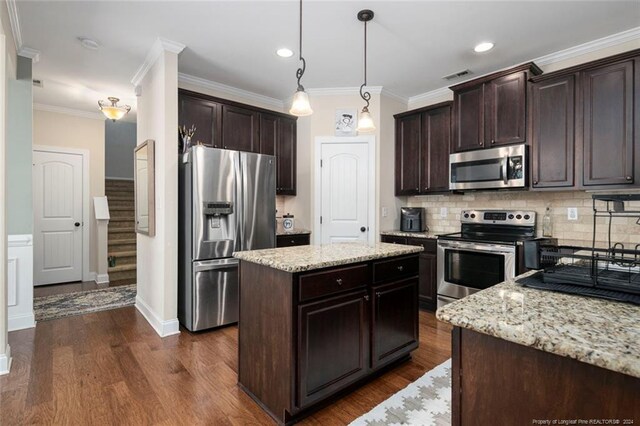 kitchen featuring a center island, appliances with stainless steel finishes, light stone counters, dark wood-type flooring, and pendant lighting