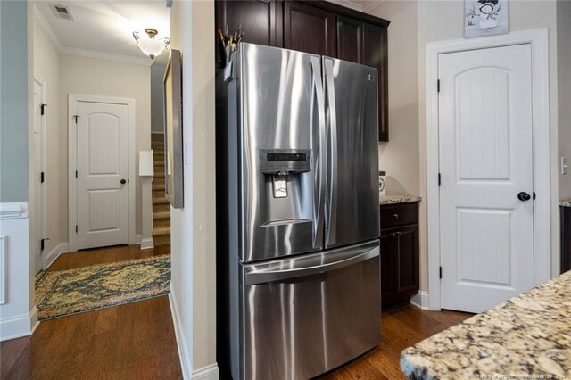 kitchen featuring dark wood-type flooring, stainless steel fridge, light stone counters, and ornamental molding