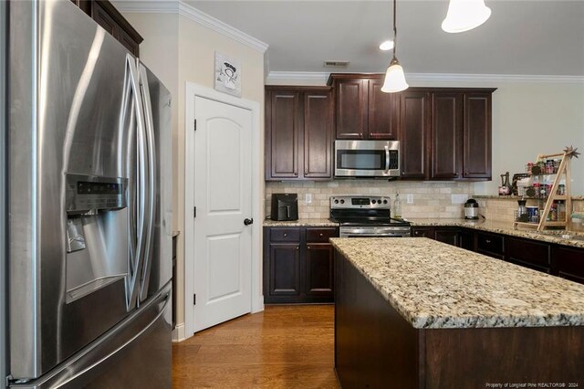 kitchen with light stone countertops, appliances with stainless steel finishes, a center island, hanging light fixtures, and dark wood-type flooring