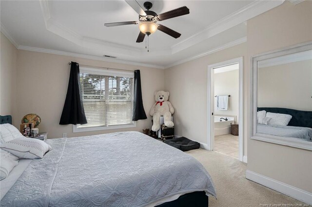 carpeted bedroom featuring a tray ceiling, ceiling fan, ensuite bathroom, and ornamental molding