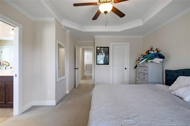 carpeted bedroom featuring crown molding, ceiling fan, ensuite bathroom, and a tray ceiling