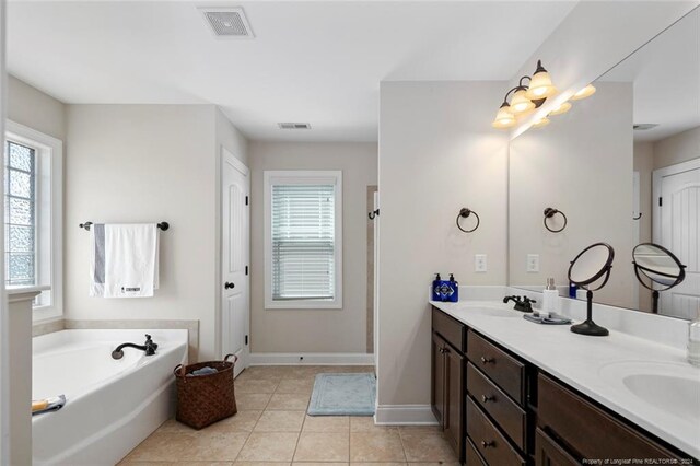 bathroom featuring tile patterned flooring, a healthy amount of sunlight, a tub to relax in, and vanity