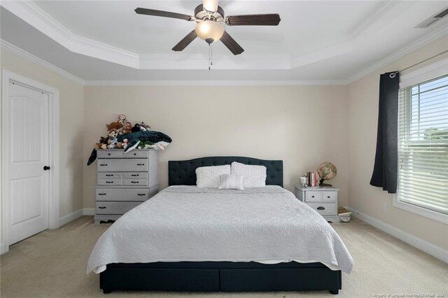 carpeted bedroom with ceiling fan, a raised ceiling, and crown molding