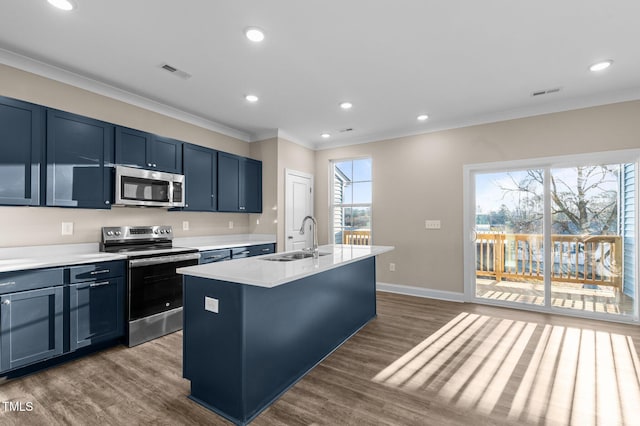 kitchen with a kitchen island with sink, dark wood-type flooring, crown molding, sink, and appliances with stainless steel finishes