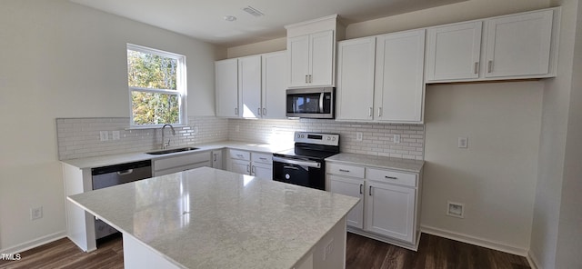 kitchen featuring stainless steel appliances, a sink, a center island, and decorative backsplash