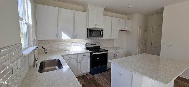 kitchen featuring a sink, decorative backsplash, electric range oven, stainless steel microwave, and dark wood finished floors