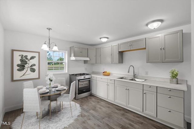 kitchen with decorative light fixtures, wood-type flooring, an inviting chandelier, sink, and gas range