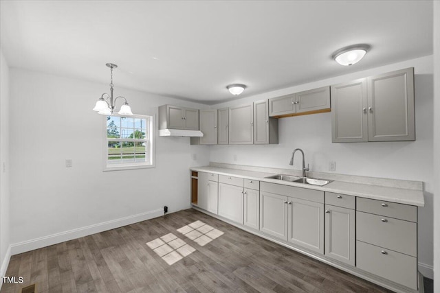 kitchen featuring dark hardwood / wood-style floors, hanging light fixtures, sink, gray cabinets, and a chandelier