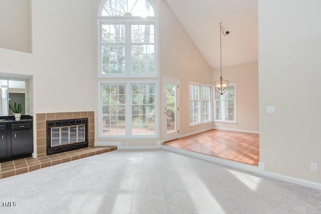 unfurnished living room featuring baseboards, carpet floors, high vaulted ceiling, and a fireplace