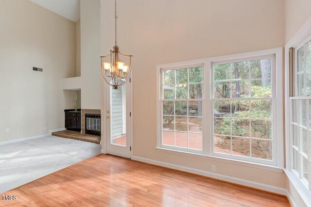 unfurnished dining area with a high ceiling, baseboards, visible vents, and a chandelier