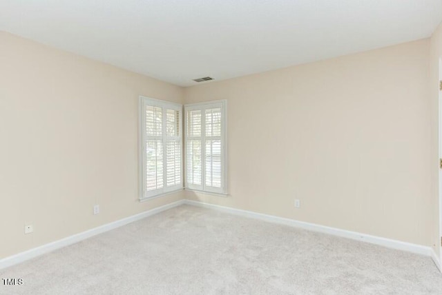 spare room with visible vents, light carpet, and baseboards