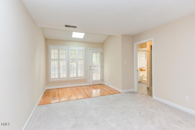 spare room featuring a skylight, carpet, visible vents, and baseboards