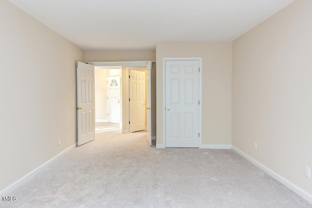 unfurnished bedroom featuring baseboards and light carpet