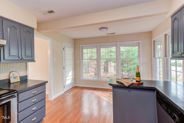 interior space with dark countertops, visible vents, backsplash, a healthy amount of sunlight, and stainless steel appliances