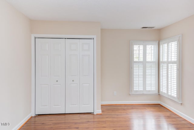 unfurnished bedroom featuring a closet, baseboards, and light wood-style flooring