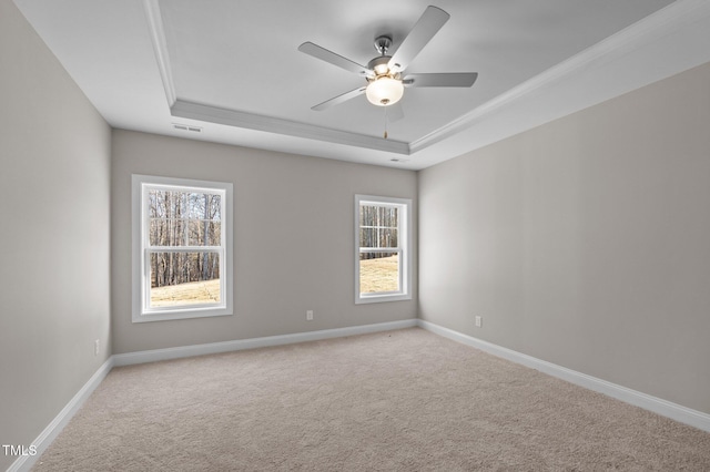 spare room with ceiling fan, a tray ceiling, and light carpet