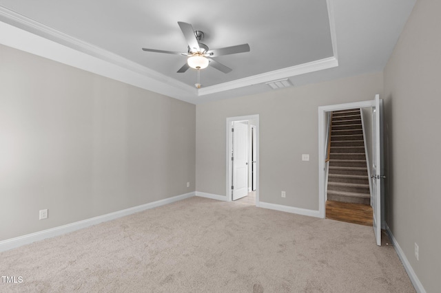 unfurnished room with ceiling fan, ornamental molding, a tray ceiling, and light carpet