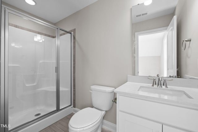 bathroom featuring toilet, wood-type flooring, vanity, and a shower with shower door