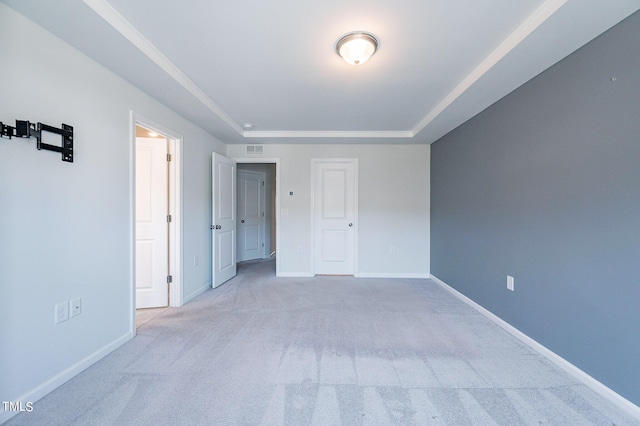 unfurnished bedroom featuring a tray ceiling, carpet, visible vents, and baseboards