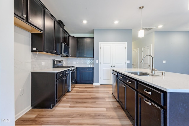 kitchen featuring stainless steel appliances, tasteful backsplash, visible vents, light wood-style flooring, and a sink