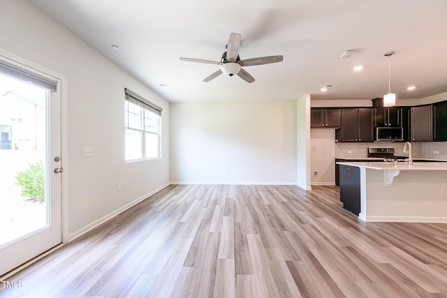 kitchen with stainless steel appliances, baseboards, light wood-style floors, light countertops, and decorative backsplash