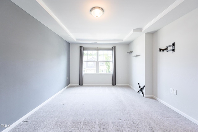 carpeted empty room featuring baseboards and a tray ceiling