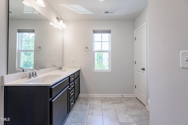 full bathroom featuring double vanity, a sink, visible vents, and baseboards