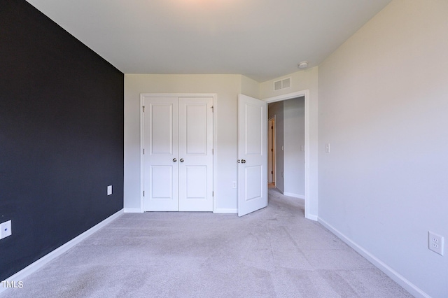 unfurnished bedroom with light carpet, baseboards, visible vents, and a closet