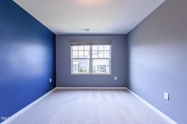 unfurnished room with carpet floors, visible vents, and baseboards