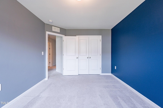 unfurnished bedroom with a closet, carpet, visible vents, and baseboards