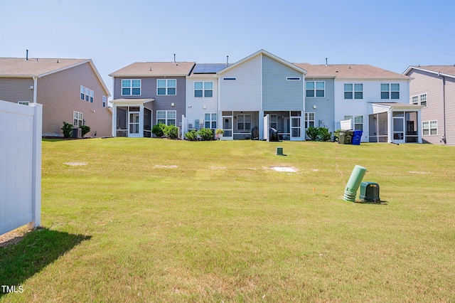 rear view of house with a sunroom, a residential view, central AC unit, and a yard